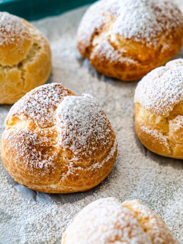 frozen mini cream puffs dusted with powder sugar on a baking tray