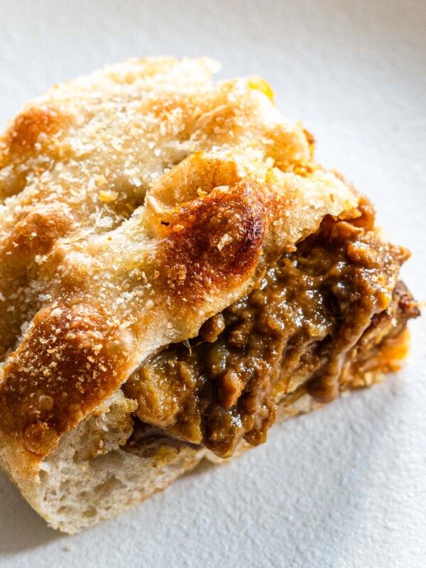 kare pan focaccia on a white plate stuffed with japanese curry and cheese, topped with panko