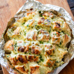 cream cheese garlic pull apart focaccia on tin foil on a wooden cutting board