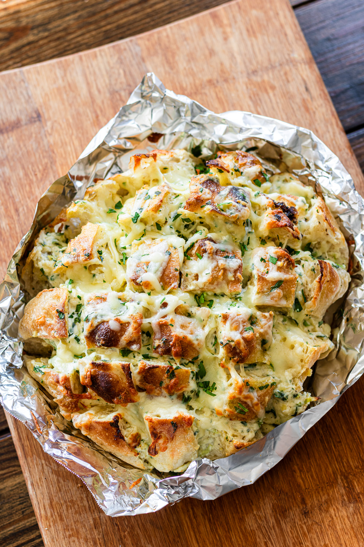 cream cheese garlic pull apart focaccia on tin foil on a wooden cutting board