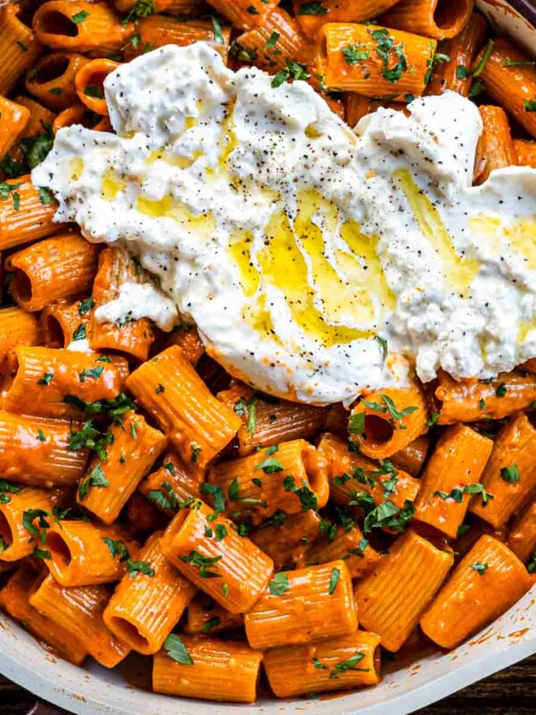 miso tomato vodka pasta in a pan with burrata on top drizzled with olive oil and garnished with parsley