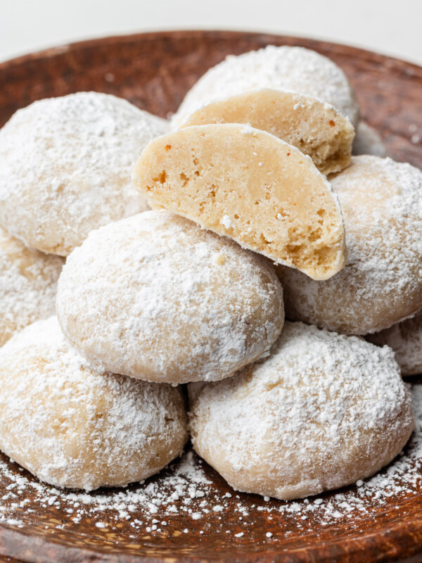 brown butter snowball cookies on a brown plate with one cut in half