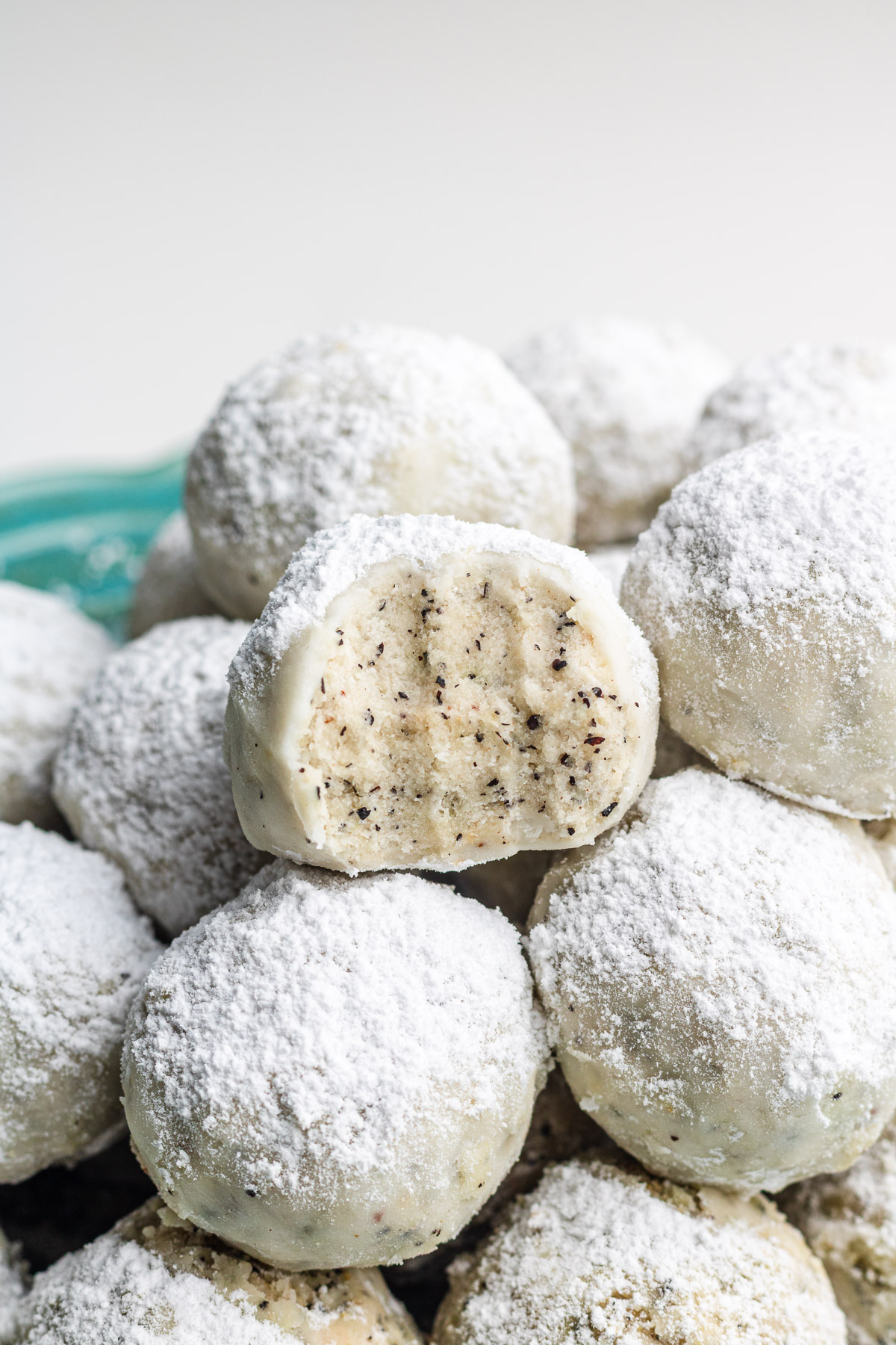 earl grey snowball cookies with a bite taken out of it stacked on other snowball cookies