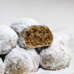 hojicha snowball cookies with a bite taken out of it stacked on other cookies