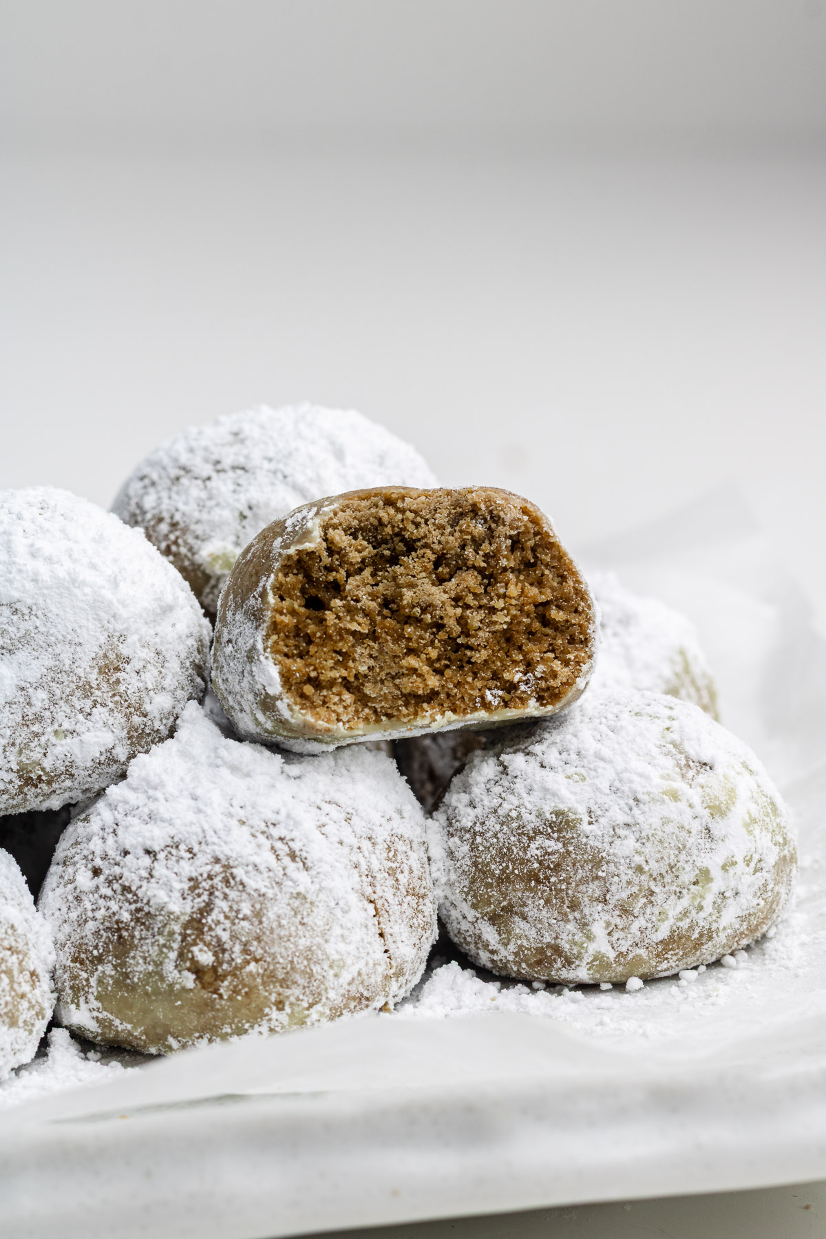 hojicha snowball cookies with a bite taken out of it stacked on other cookies