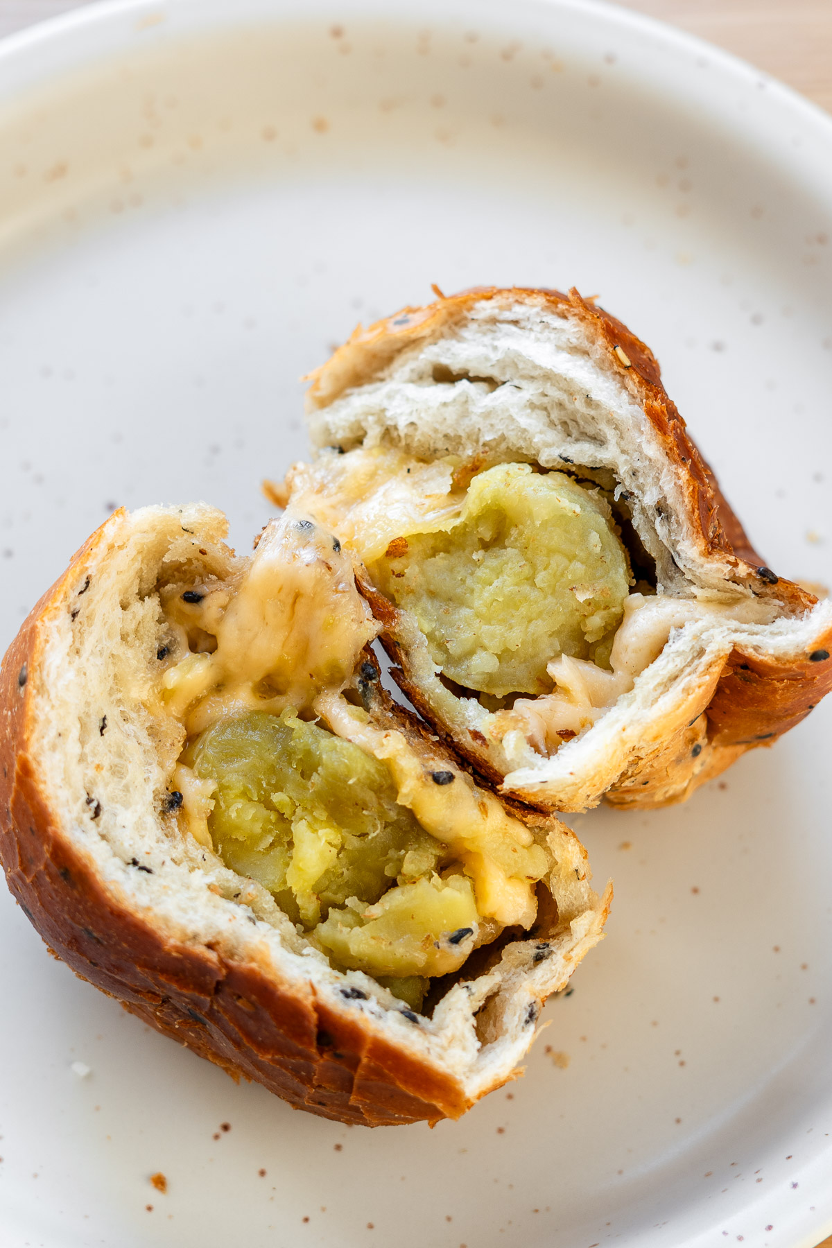 sesame bread filled with butter, cheese, japanese sweet potato split in half on a white plate