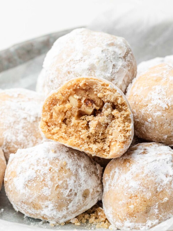 kinako nut cookies with coated in powdered sugar stacked on other snowball cookies