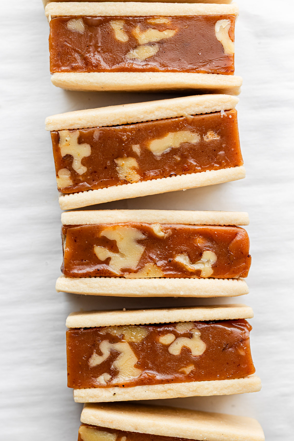 caramel walnut sandwich cookies lined up on parchment paper