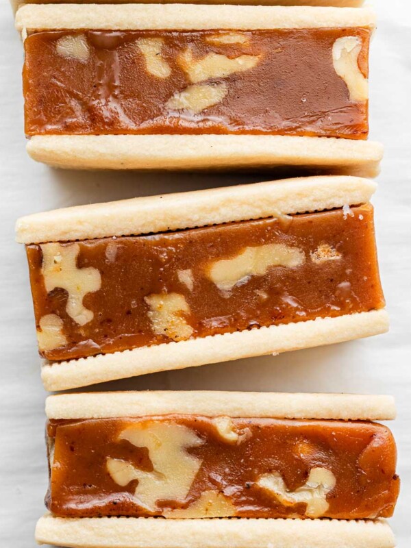 caramel sandwich cookies with walnuts lined up on parchment paper