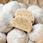 sesame snowball cookies cut in half in a bowl lined with parchment paper