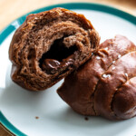 chocolate salt bread on a green rimmed dessert plate with melted chocolate inside the butterhole