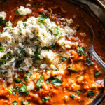spicy lasagna soup in a bowl topped with herby ricotta with a spoon on the side