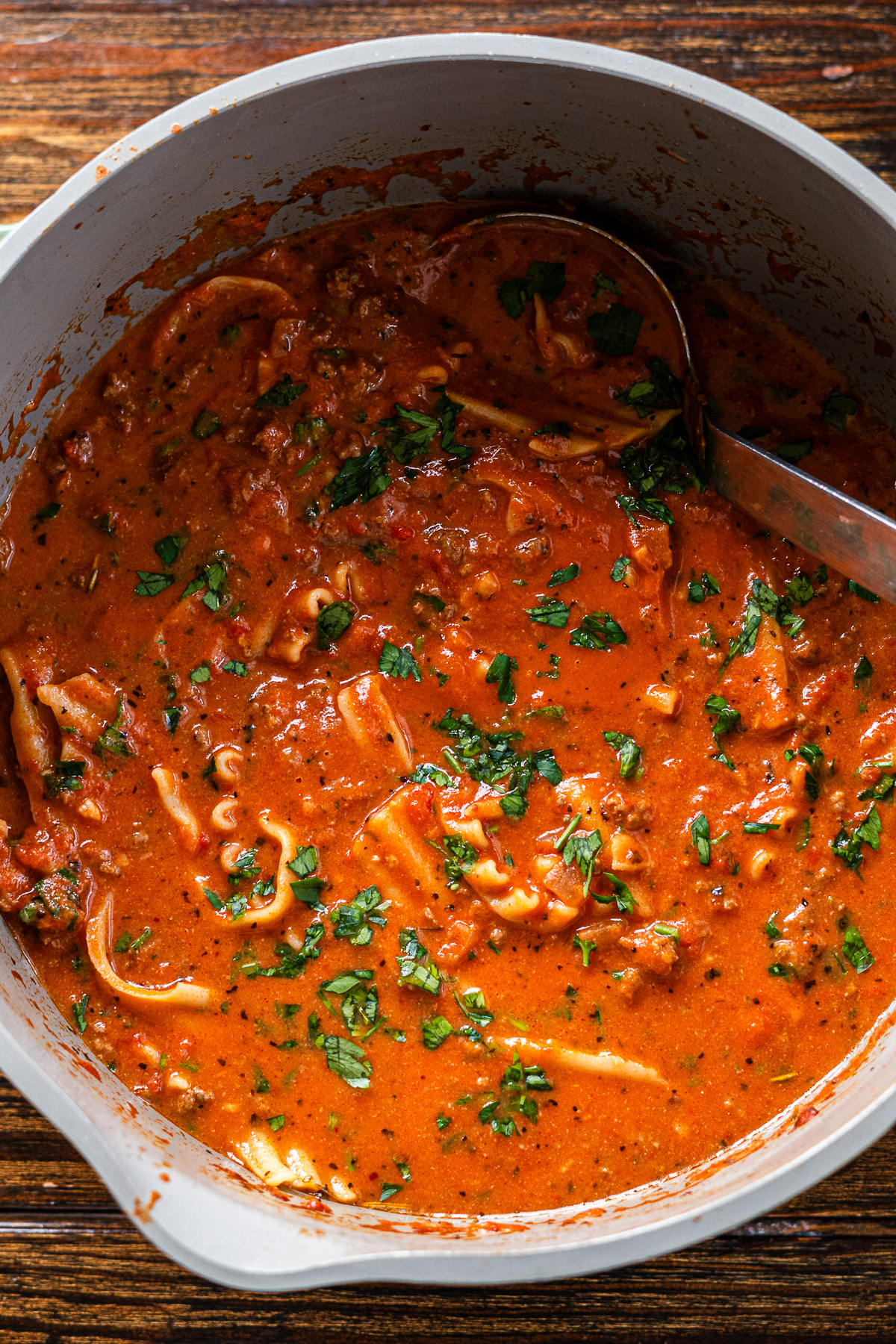 spicy lasagna soup in a large green pot topped with parsley