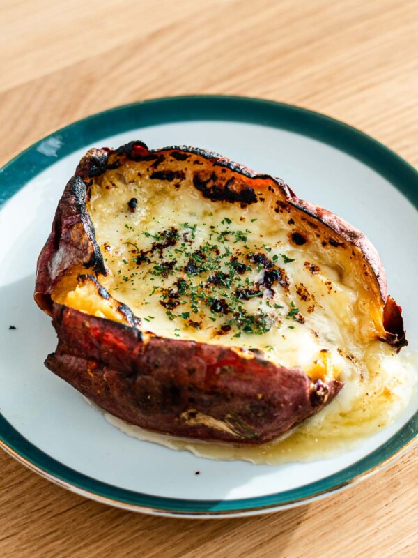 cheesy honey butter japanese sweet potato on a green rimmed plate with melty cheese oozing out