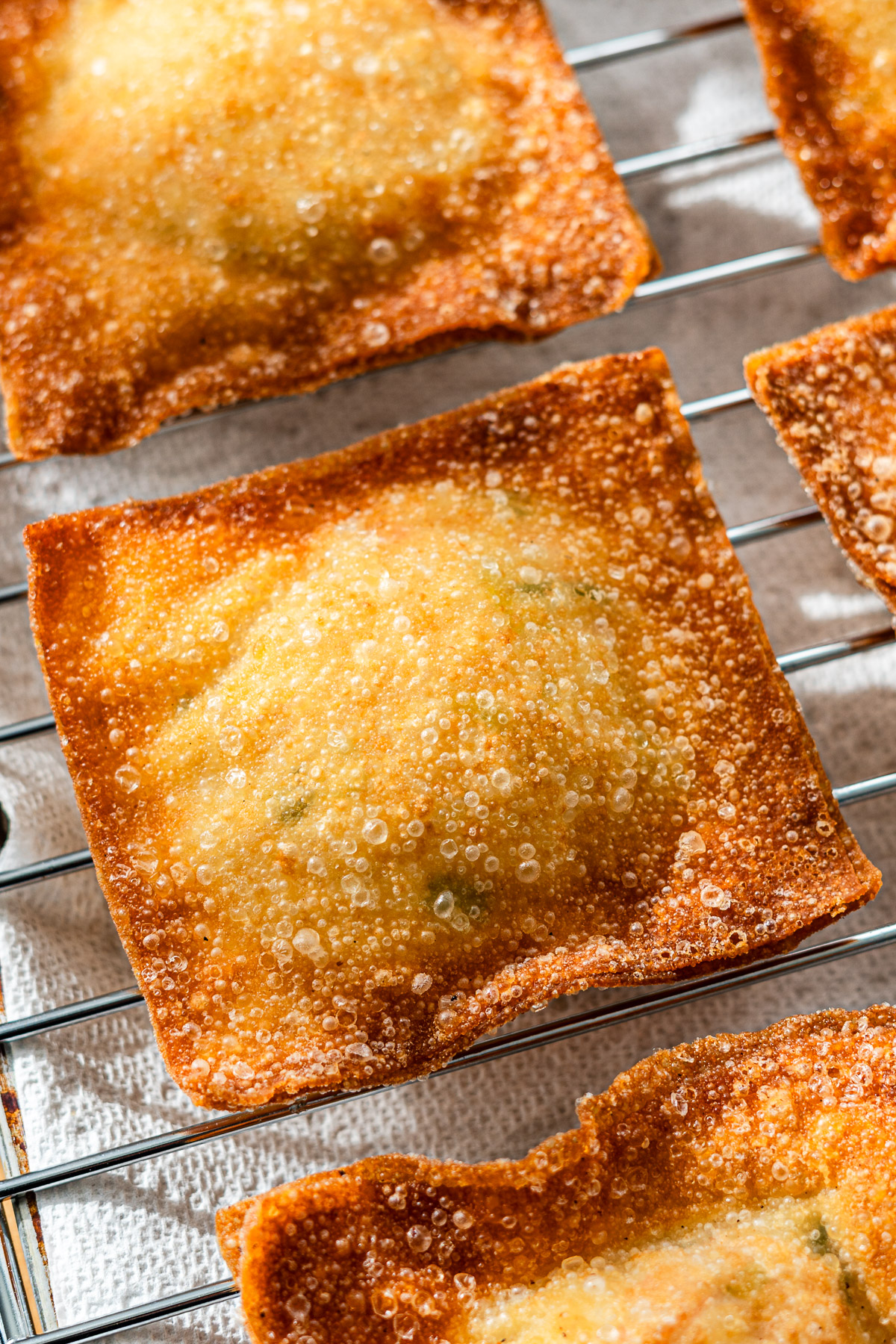 golden fried crab rangoon stuffed wontons on a wire rack