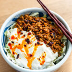 creamy mapo tofu cabbage salad in a blue bowl drizzled with chili crisp