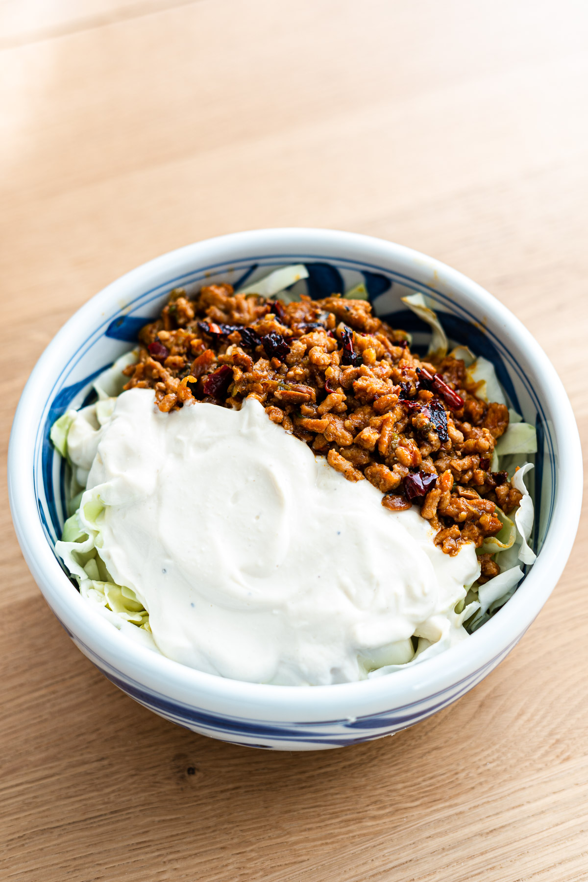 spicy pork mince and blended tofu topped over shredded cabbage in a blue bowl