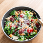 caesar salad with lap cheong, lettuce, tomato, grilled chicken and fried wonton chilps in a brown bowl