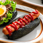 onigiri dog with sausage and ketchup on a white plate