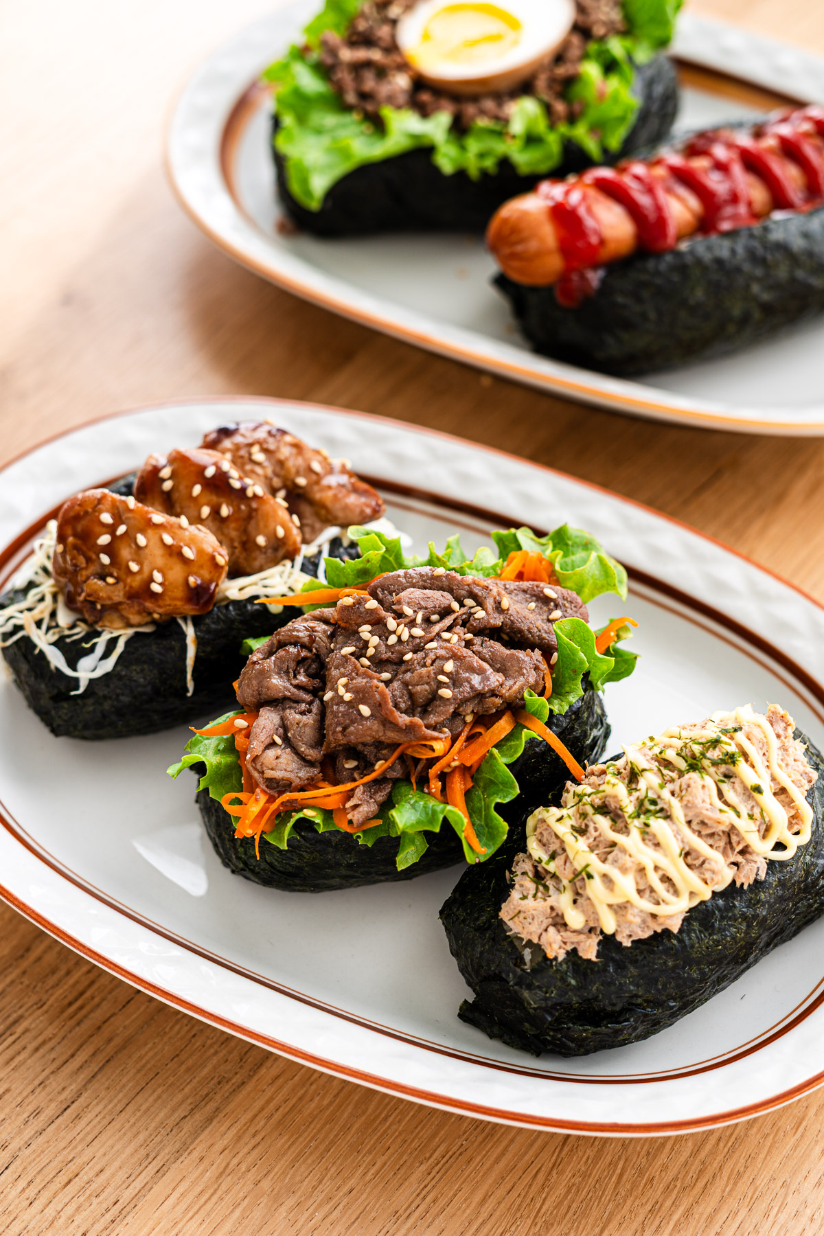 rice hot dogs with teriyaki chicken, yakiniku, carrots, lettuce and tuna mayo on a oval plate