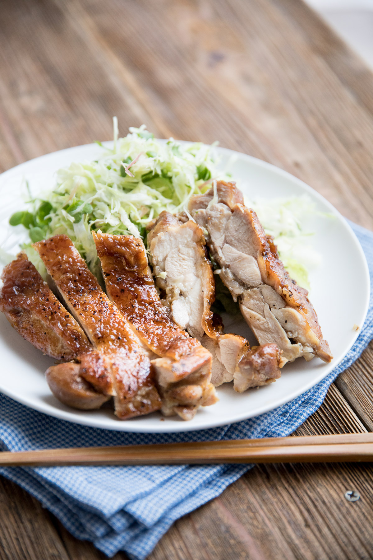 cross section of teriyaki chicken on a white plate with crispy skin and glossy glaze