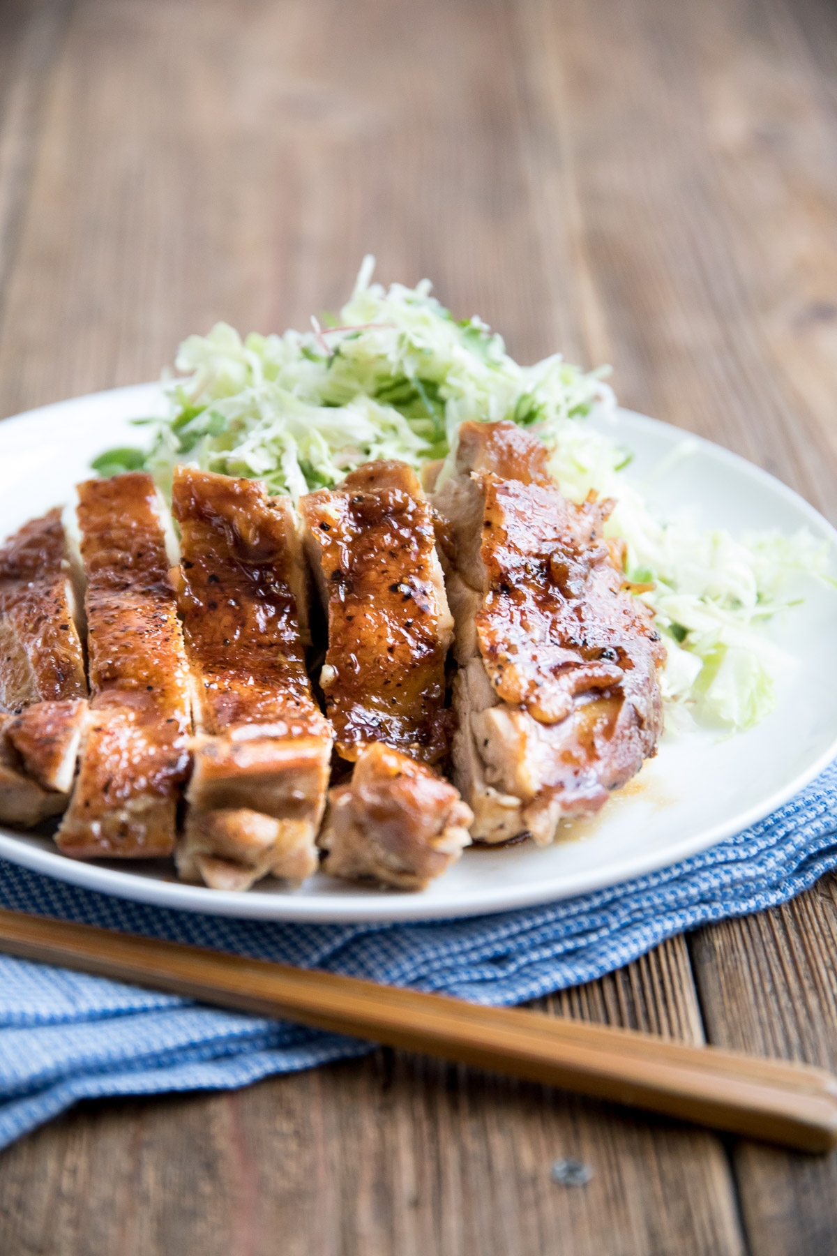 chicken teriyaki on a white plate with cabbage salad
