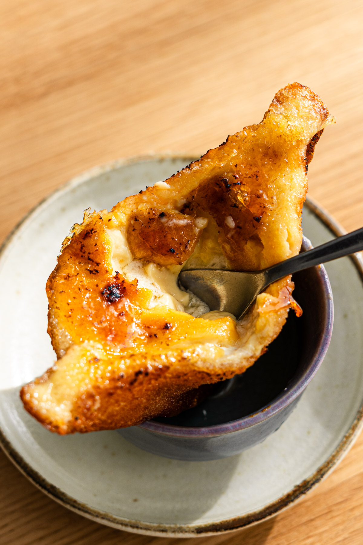 japanese fried creme brulee sandwich with a spoon cracking it on a taco holder