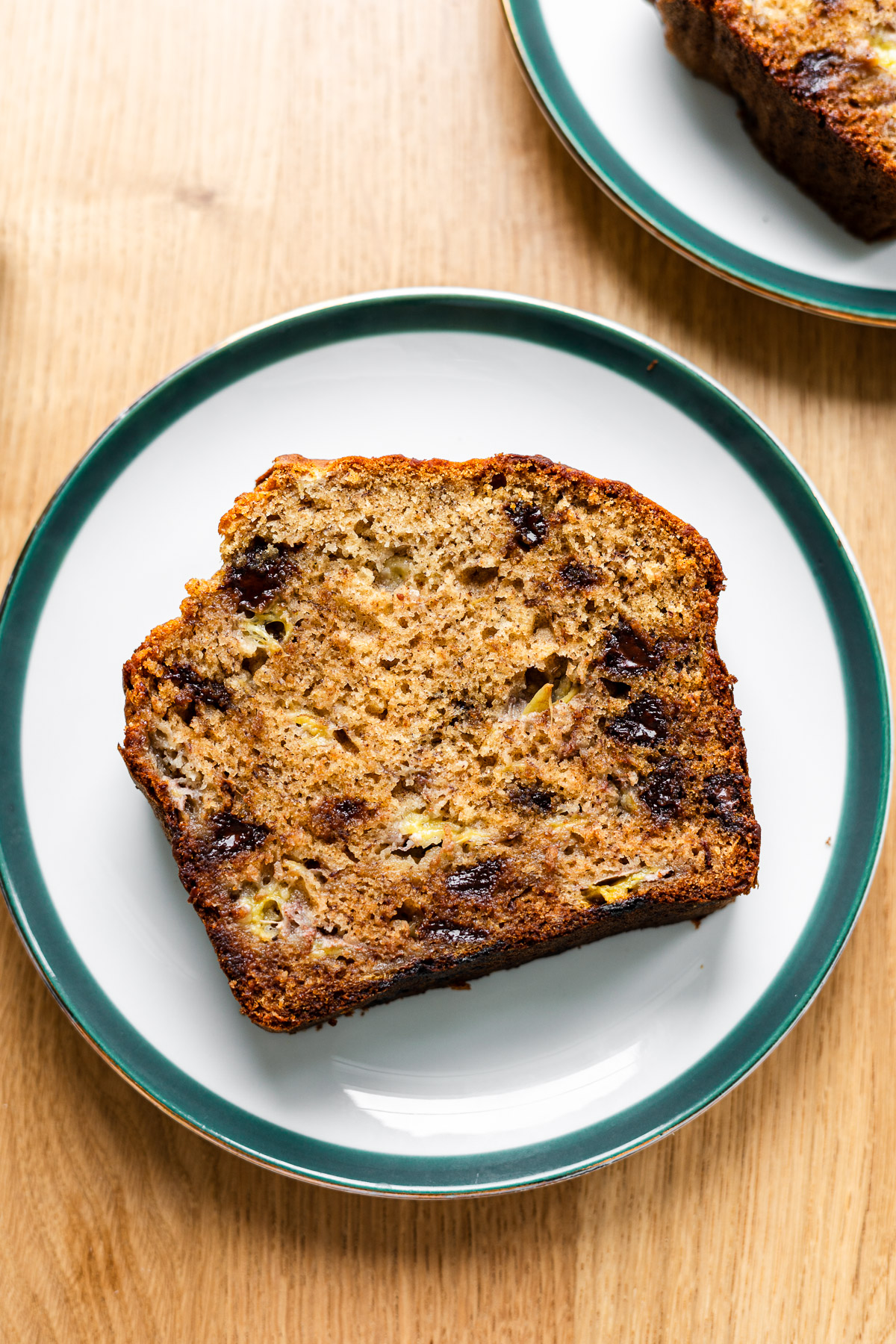 moist brown butter banana bread with chocolate chips on a green rimmed plate