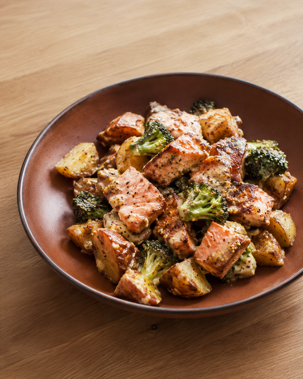 salmon potato salad with broccoli tossed in a creamy honey mustard dressing on a terracotta shallow bowl