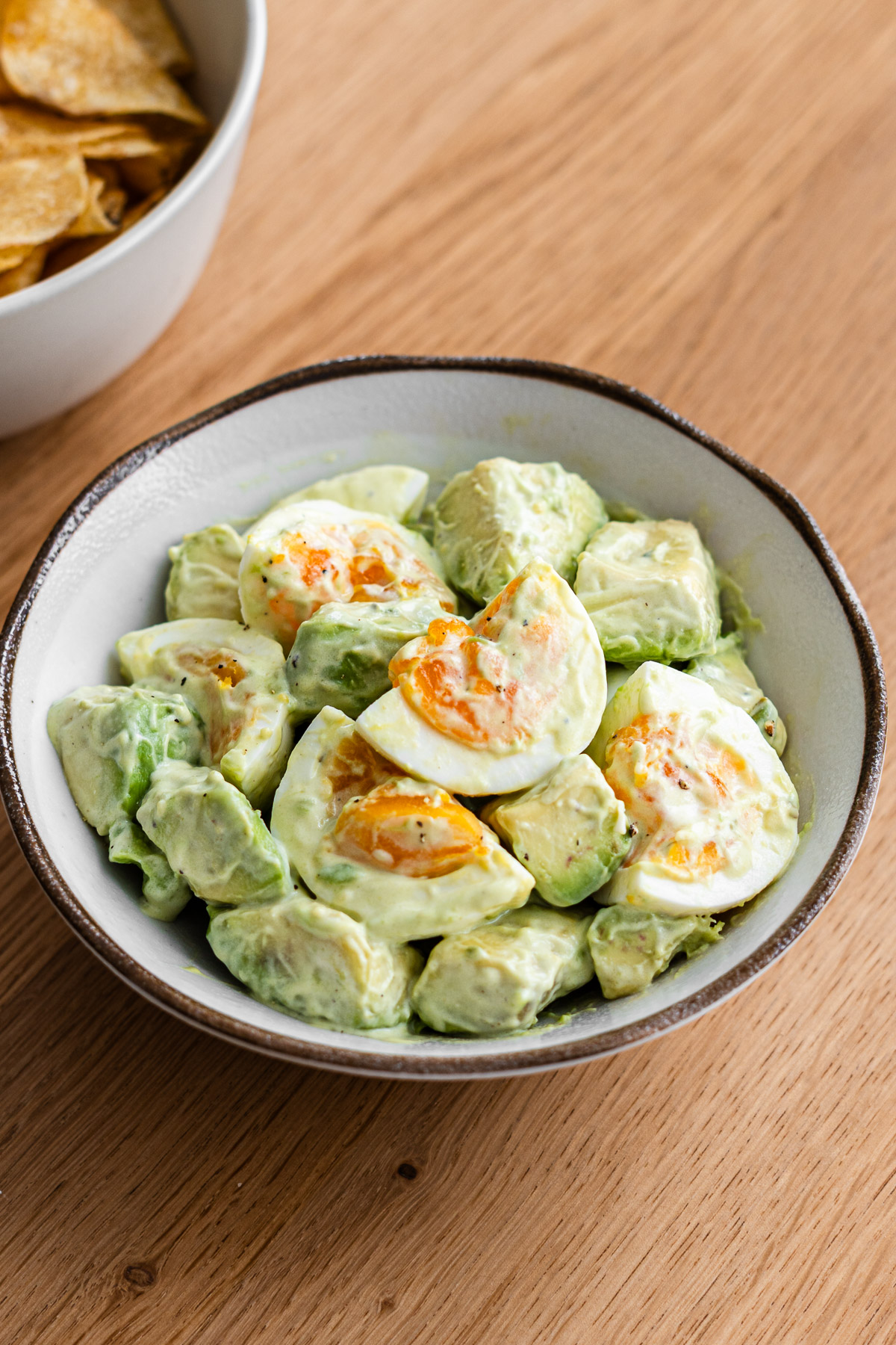 avocado egg salad in a brown rim side dish bowl tossed in kewpie mayo